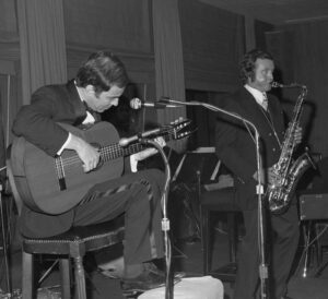 Black and white photo of Joao Gilberto playing the guitar and Stan Getz playing the saxophone.