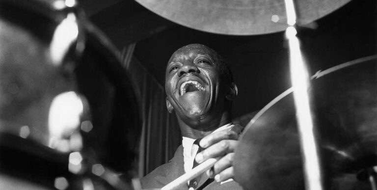 Black and white portrait of Art Blakey playing the drums.