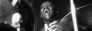 Black and white portrait of Art Blakey playing the drums.