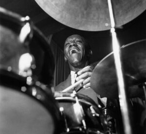 Black and white portrait of Art Blakey playing the drums.