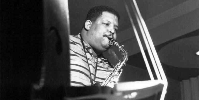 Black and white portrait of Cannonball Adderley playing the saxophone.