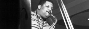 Black and white portrait of Cannonball Adderley playing the saxophone.