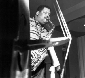 Black and white portrait of Cannonball Adderley playing the saxophone.