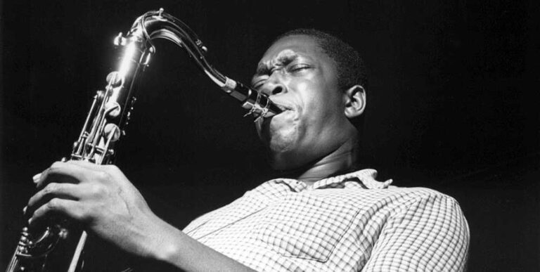 Black and white portrait of John Coltrane playing the saxophone.