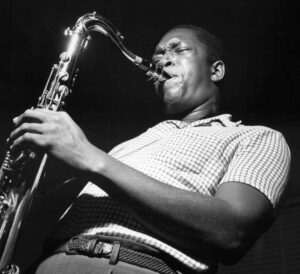 Black and white portrait of John Coltrane playing the saxophone.