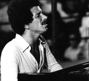 Black and white film photograph of Keith Jarrett playing piano live.